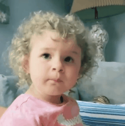 a little girl with curly hair and shirt looking at the camera