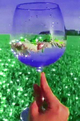 a hand holding a wine glass with pink liquid in it