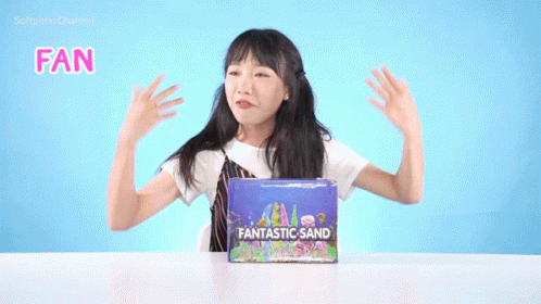 a girl is holding up her arms and standing over a box that says fan