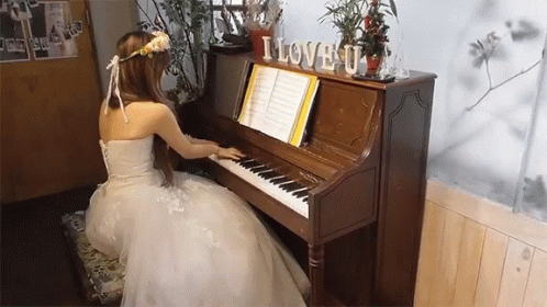 a woman wearing blue dress sitting in front of an electric piano