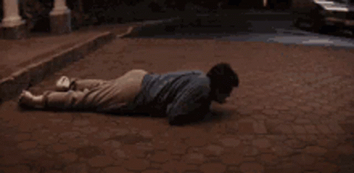 a man lays on the ground near a curb in the evening