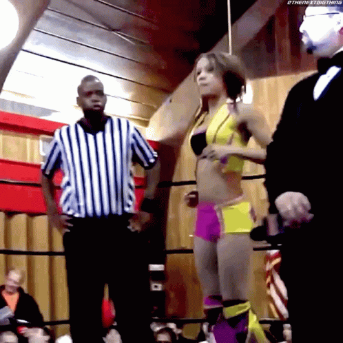 two people and an referee on a boxing ring