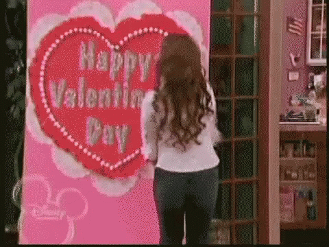 a girl standing in front of a happy valentines day heart wall