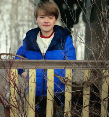 a  in an orange jacket is standing on the porch