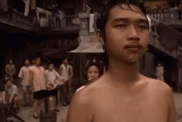 a shirtless young man stands at an alley