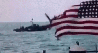 a large american flag flying over the top of a boat