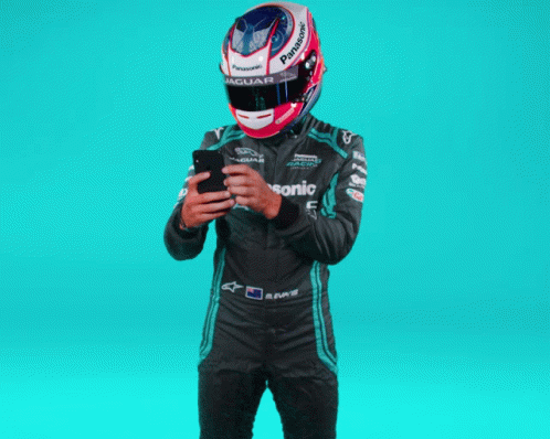 a man in a racing suit using his cell phone