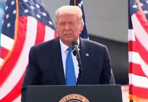 the president stands at a podium speaking from behind two american flags