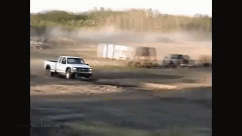 truck driving through dirt with other trucks in the background