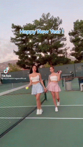 two women on a tennis court wearing skirts