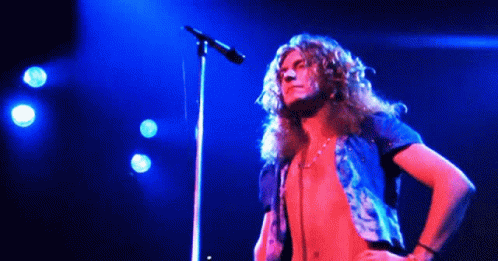 long haired guy standing in front of a microphone on stage