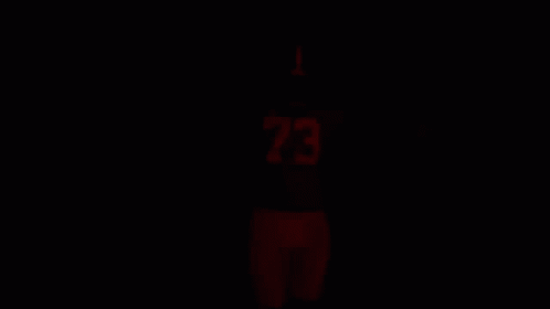 a person standing up wearing a jersey in the dark