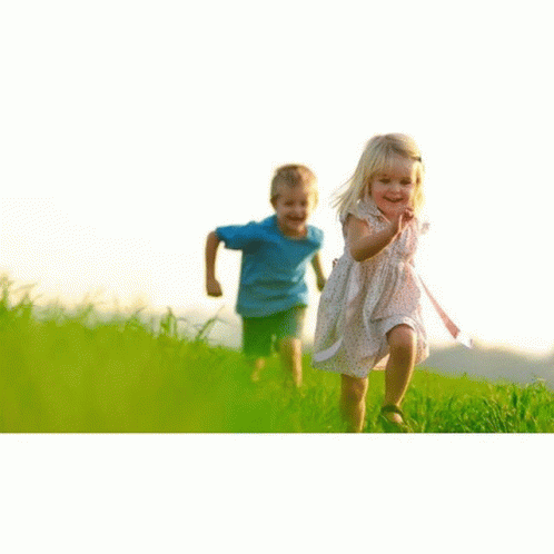two children running through grass towards a dog