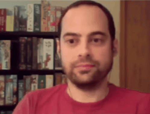 a man looking at the camera with blurry books behind him