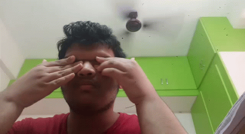 a man covering his eyes and staring in the mirror
