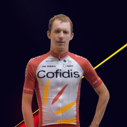 a male in a bicycle jersey stands in front of a black background