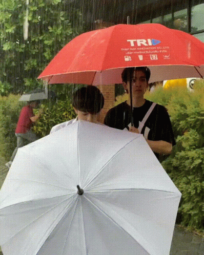 three men walk around in the rain under umbrellas
