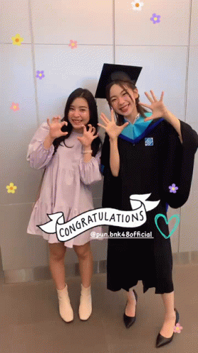 two people dressed in graduation outfits giving a peace sign