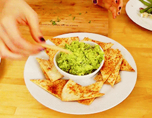 a white plate topped with guacamole and chips