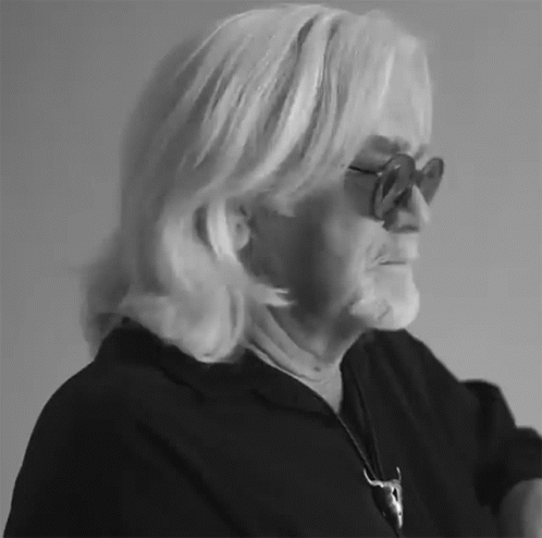 an older woman with blond hair and glasses looking off into the distance
