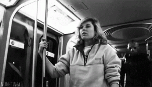 woman wearing a white sweatshirt is on a subway
