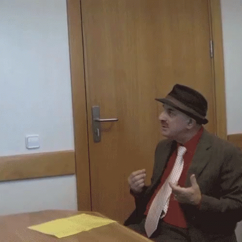man with hat and tie in room with door