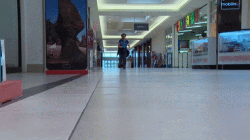 man walking inside an empty shopping mall next to their luggage