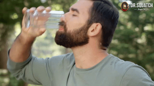 a bearded man holding up a bottle of water