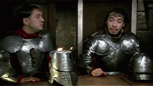 two men in golden armor sit down at a table