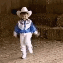 a little boy in a white suit and cowboy hat