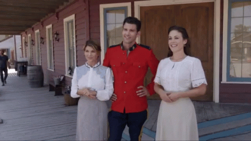 a man in uniform and two woman standing by porch