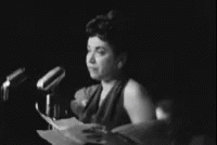 a woman is sitting in front of a microphone holding paper