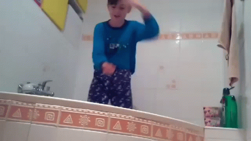 a young person brushing his hair in the mirror