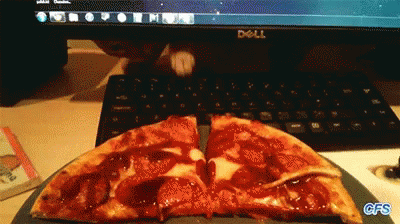 a pizza sitting on a table in front of a laptop computer