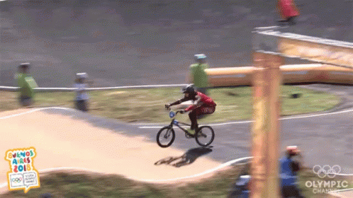 man riding bicycle over water obstacle course in olympic event