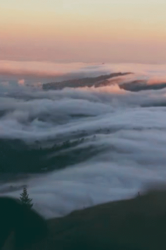 an aerial view of clouds and mountains and hills
