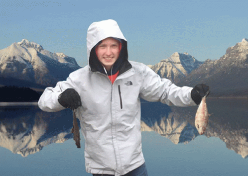 woman in snow coat holding fish by mountain lake