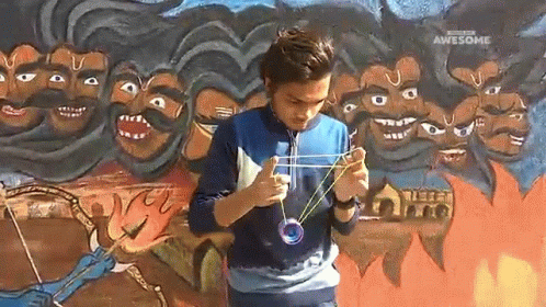 an old man playing with a string and scissors in front of a mural