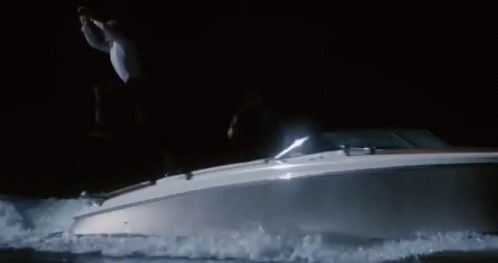 a man jumping in the air off of a boat at night