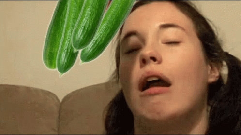 a woman blowing on green pods that are on her head