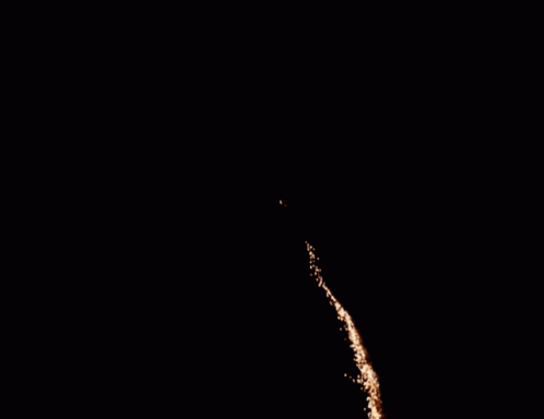 fireworks are lit in the dark sky with two people watching them