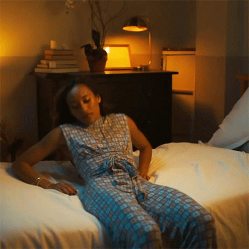 woman laying in bed with lamp and nightstand beside her