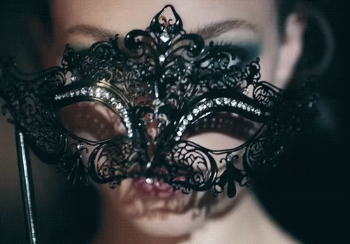 a woman in black with a silver mask