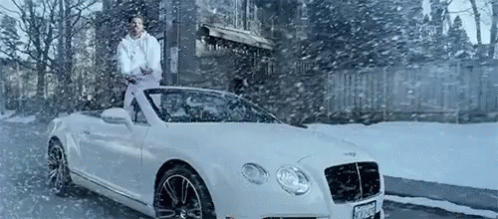 the man stands on the roof of the car in the snow