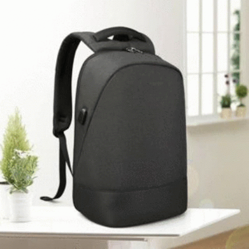 a black backpack is sitting on a table next to small plants