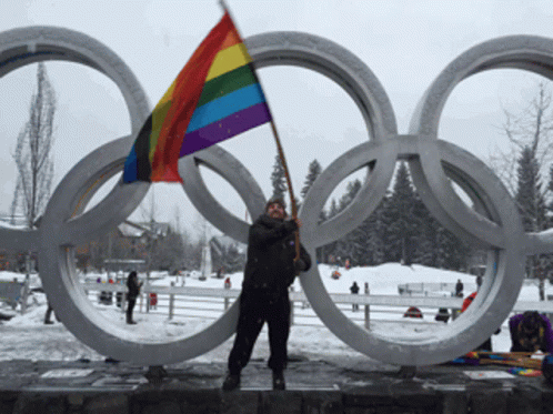 a person holding a flag stands in front of the olympic rings