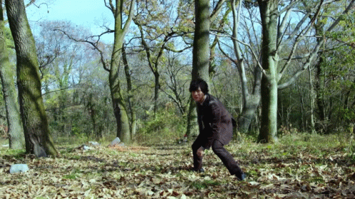 a man running in the forest towards an object