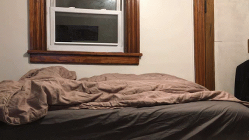 a bed sitting in a room underneath a window