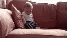 a baby sitting on top of a blue couch