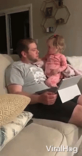 a man sitting on a couch next to a little girl